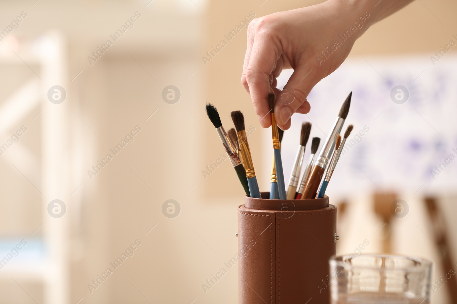 Photo of Watercolorist taking brush from holder in workshop, closeup. Space for text