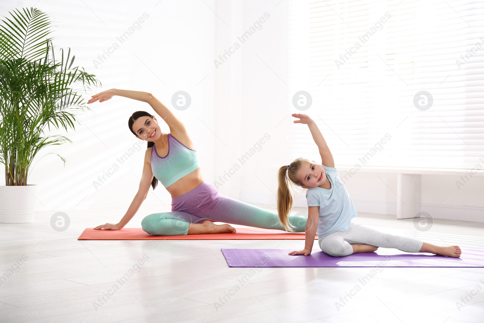Photo of Woman and daughter doing yoga together at home. Fitness lifestyle