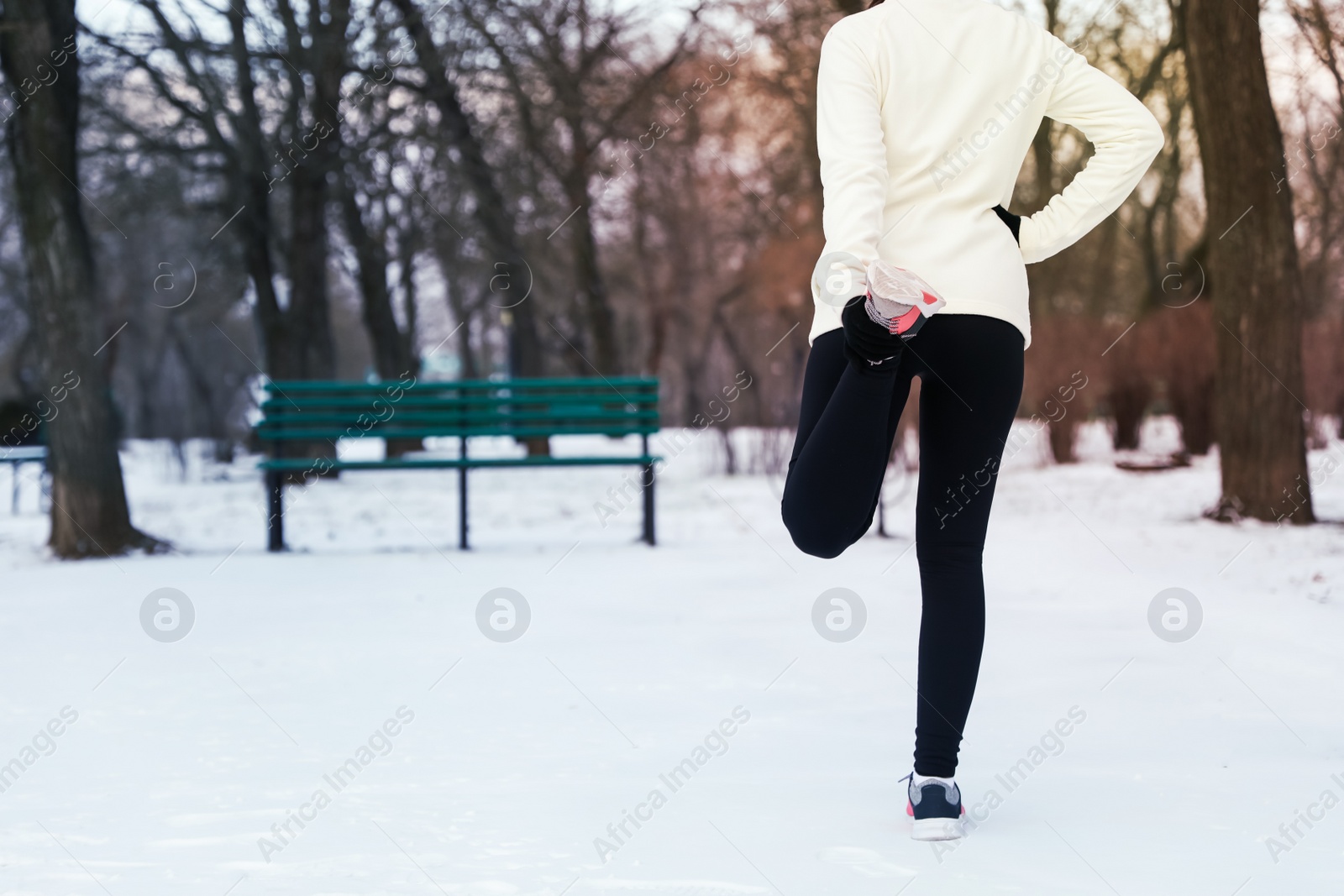 Photo of Woman doing sports exercises in winter park, closeup