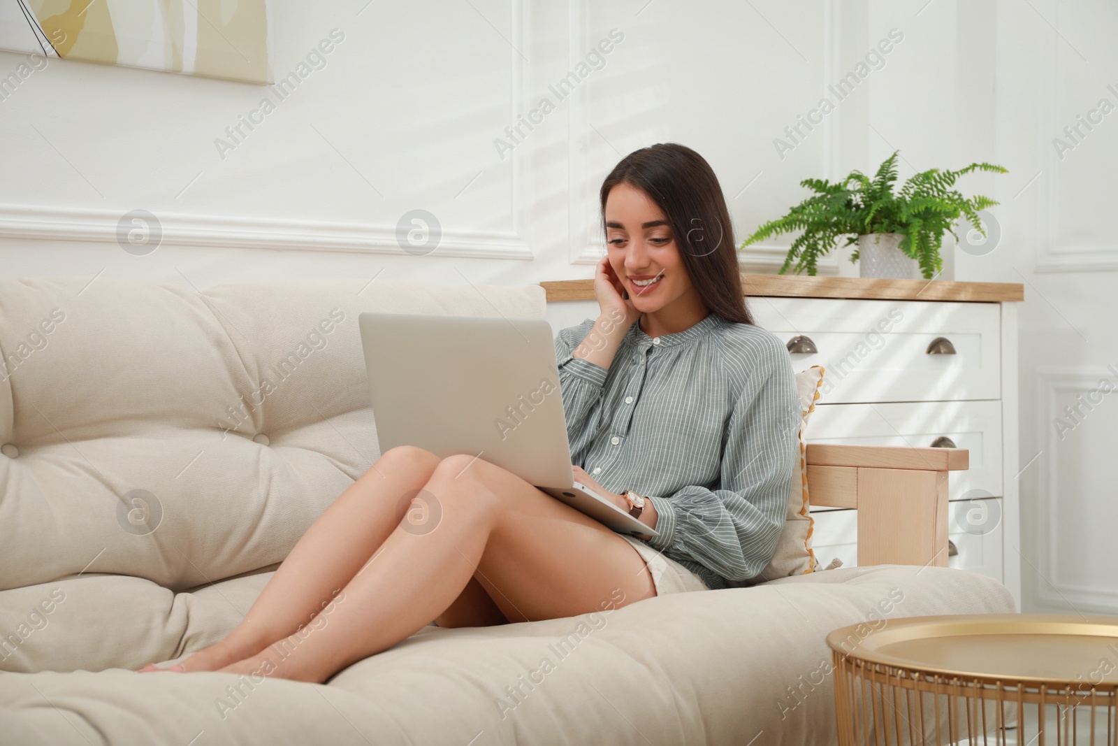 Photo of Young woman using laptop on sofa at home. Internet shopping