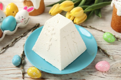 Photo of Traditional cottage cheese Easter paskha and dyed eggs on white wooden table