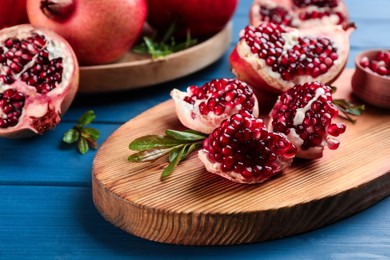 Photo of Delicious ripe pomegranates on blue wooden table, closeup