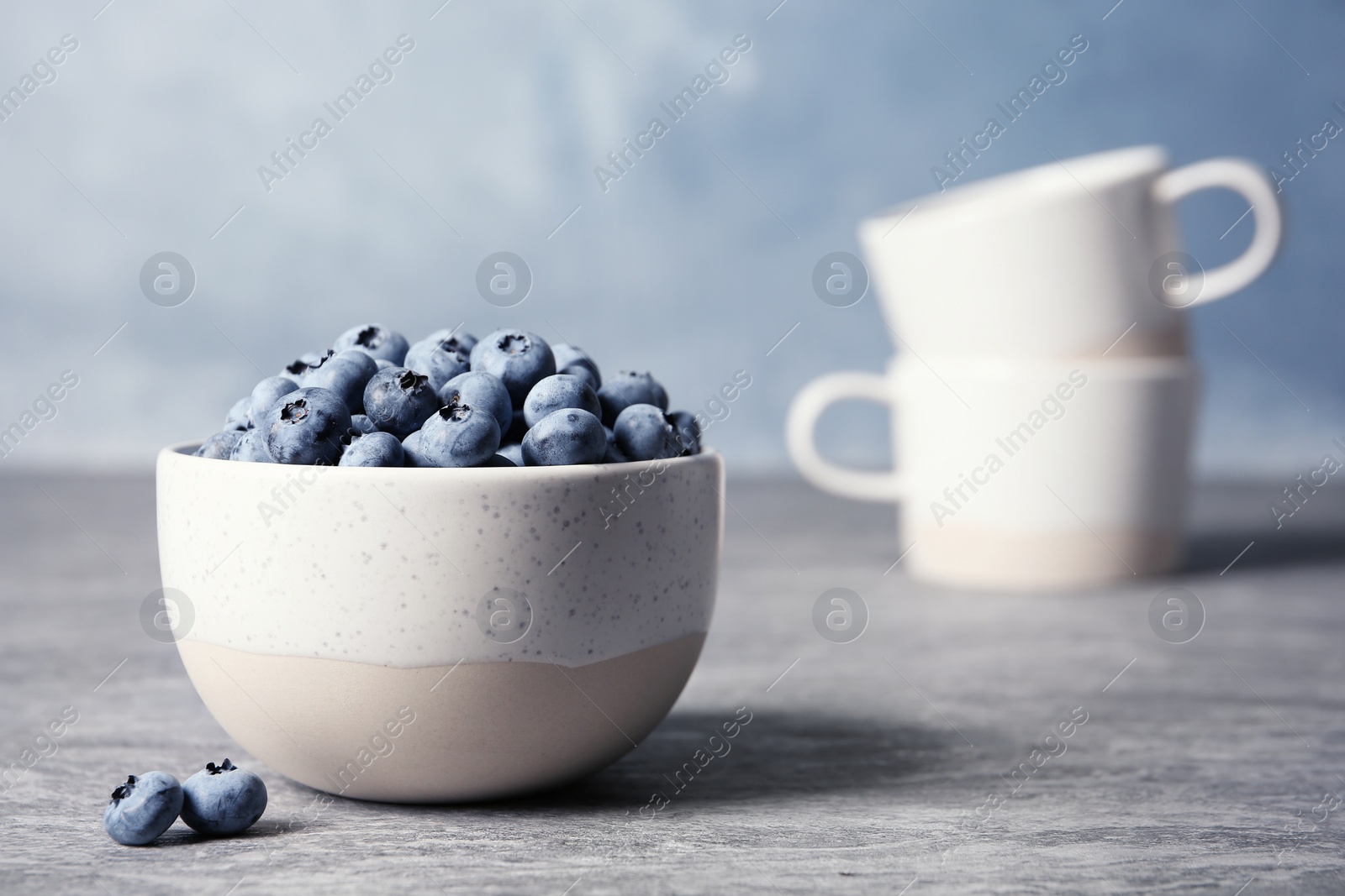 Photo of Crockery with juicy and fresh blueberries on blurred background