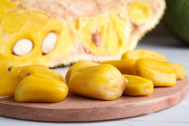 Photo of Delicious exotic jackfruit bulbs on white wooden table, closeup