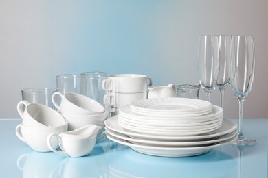 Set of clean dishes and glasses on light blue table