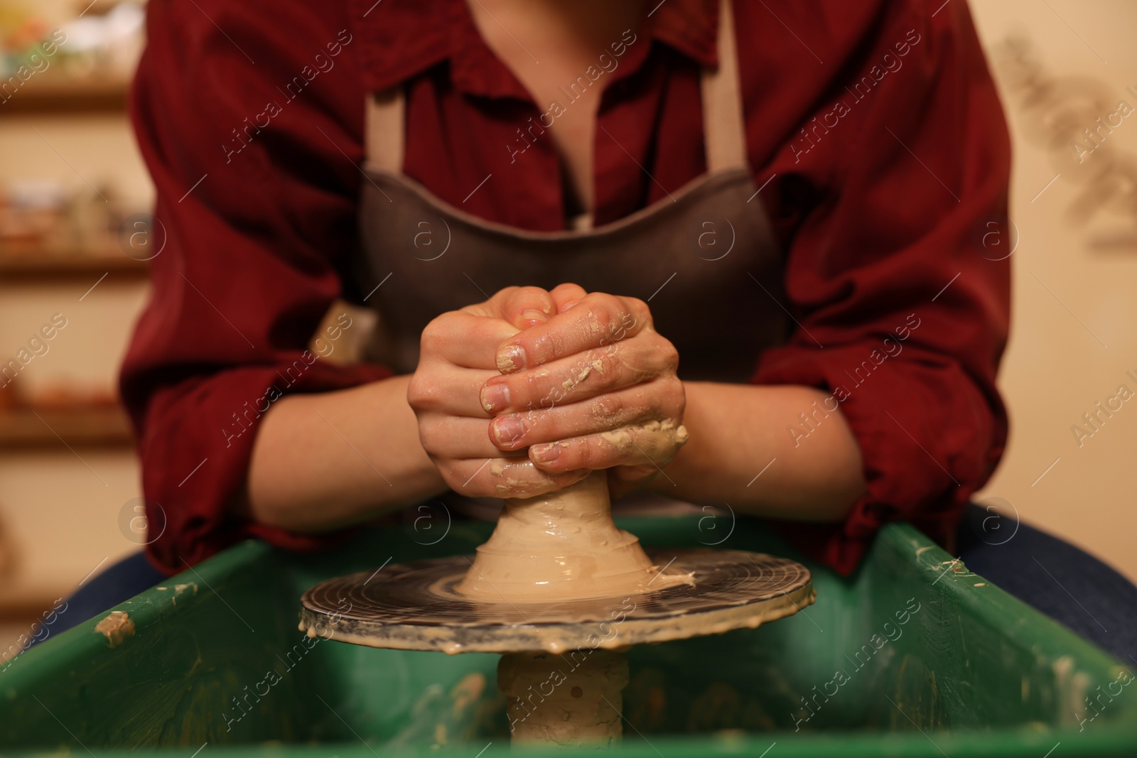 Photo of Woman crafting with clay on potter's wheel indoors, closeup