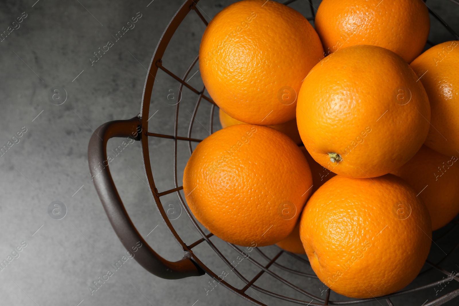 Photo of Basket with ripe oranges on grey background, top view