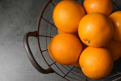 Basket with ripe oranges on grey background, top view