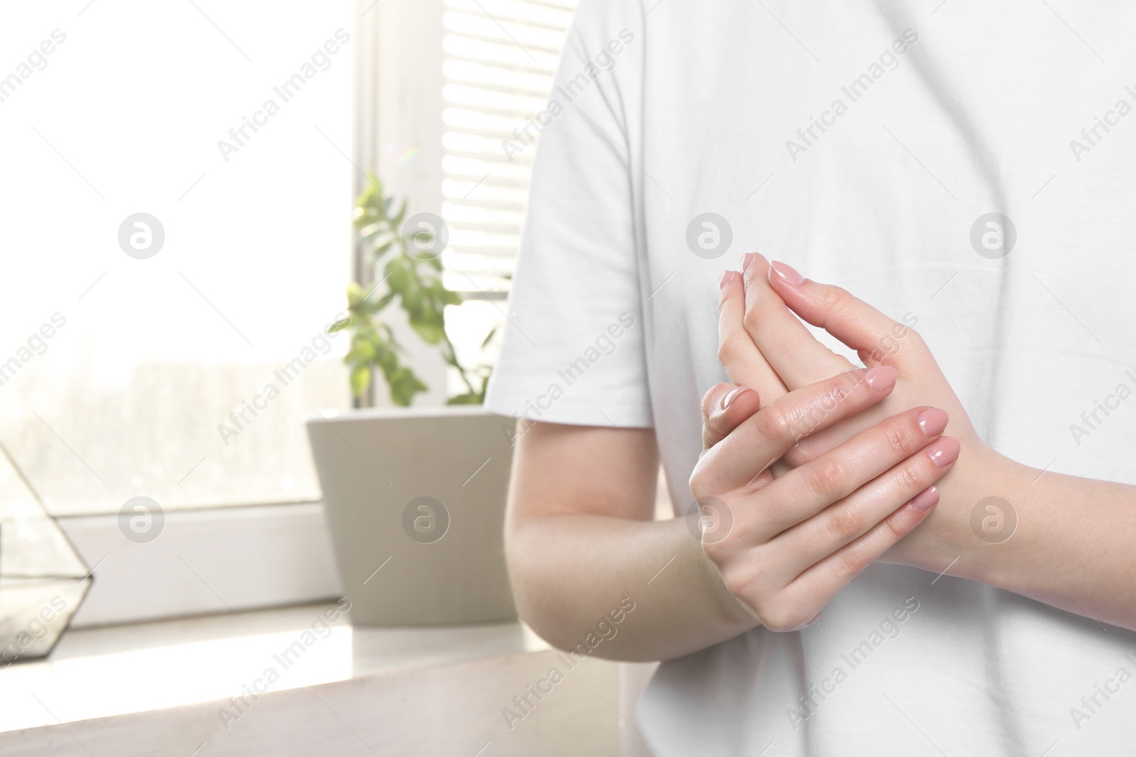 Photo of Woman applying hand cream at home, closeup