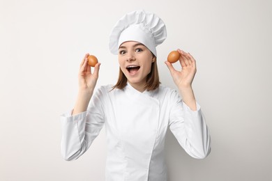 Photo of Professional chef with chicken eggs having fun on light background