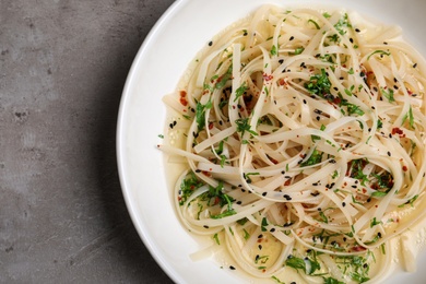 Photo of Plate of noodles with broth and herb on grey background, top view. Space for text