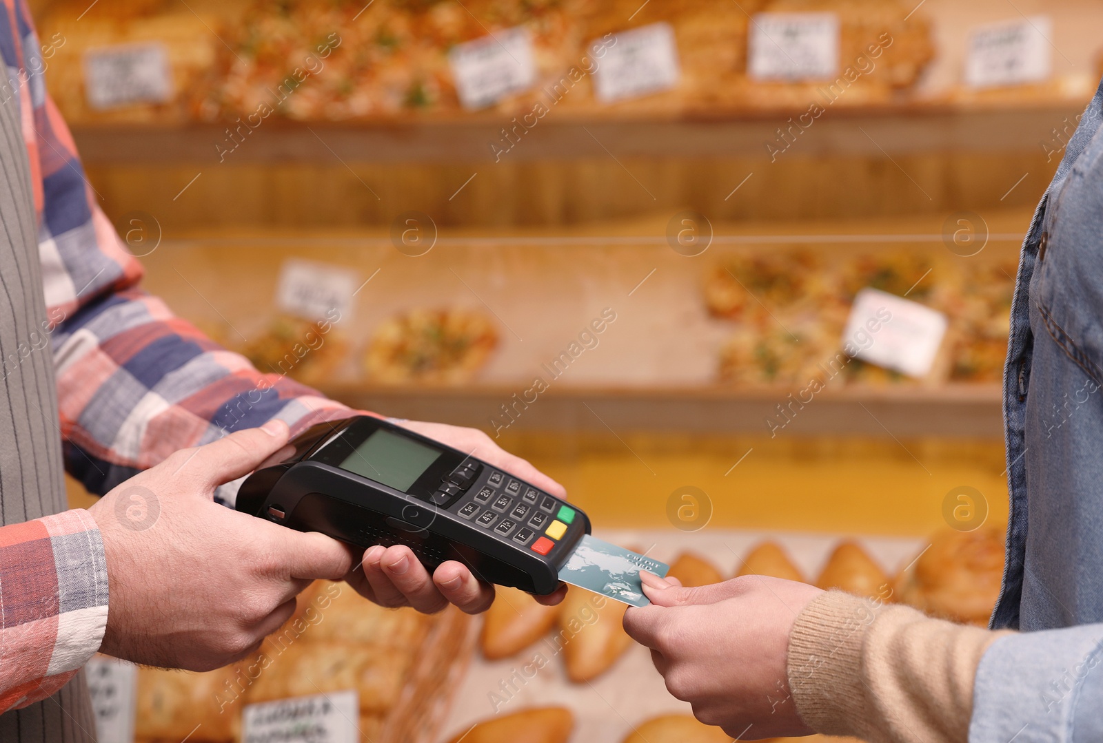 Photo of Woman using credit card for terminal payment in bakery, closeup. Space for text