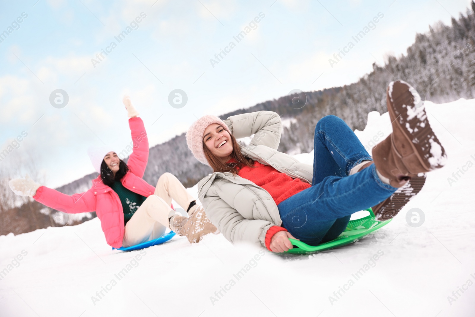 Photo of Happy friends having fun and sledding on snowy day. Winter vacation