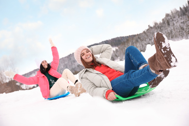 Happy friends having fun and sledding on snowy day. Winter vacation