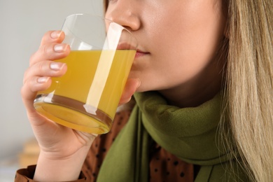 Woman drinking dissolved cold relief powder indoors, closeup