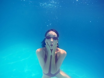 Photo of Beautiful young woman swimming in pool, underwater view