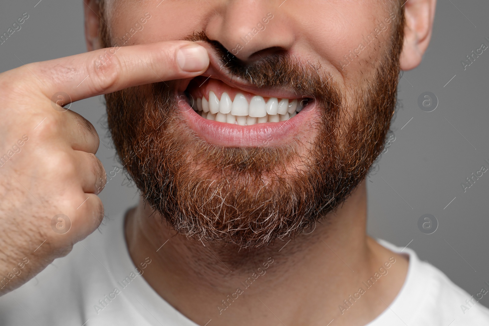 Photo of Man showing healthy gums on gray background, closeup