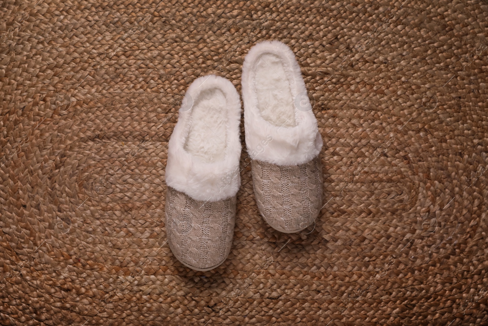 Photo of Pair of beautiful soft slippers on wicker carpet, top view