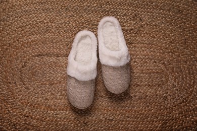 Pair of beautiful soft slippers on wicker carpet, top view