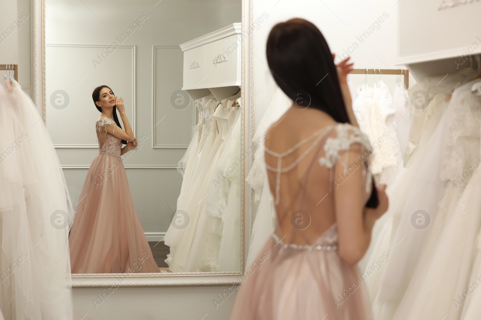 Photo of Woman trying on wedding dress in boutique