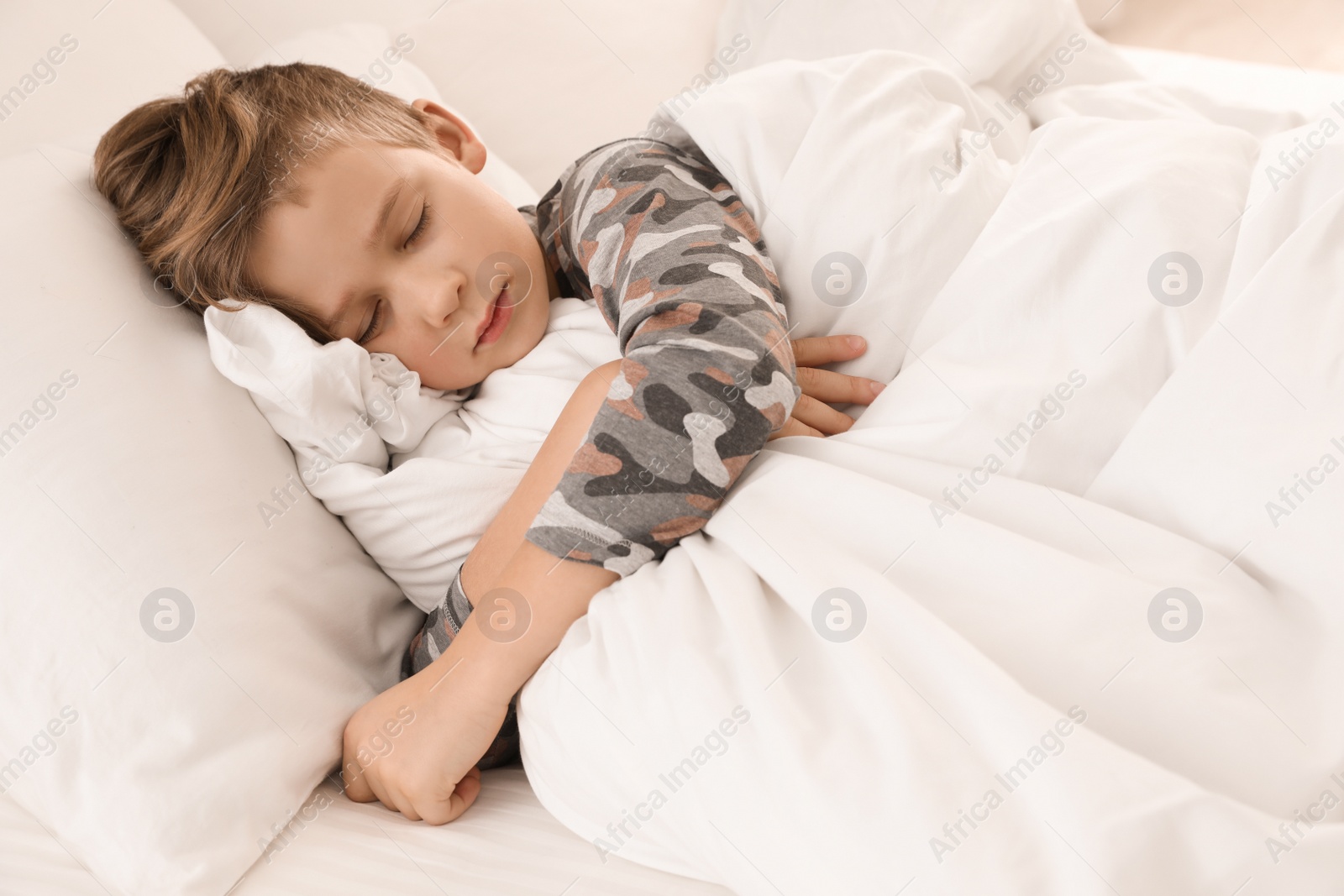 Photo of Cute tired boy sleeping in comfortable bed