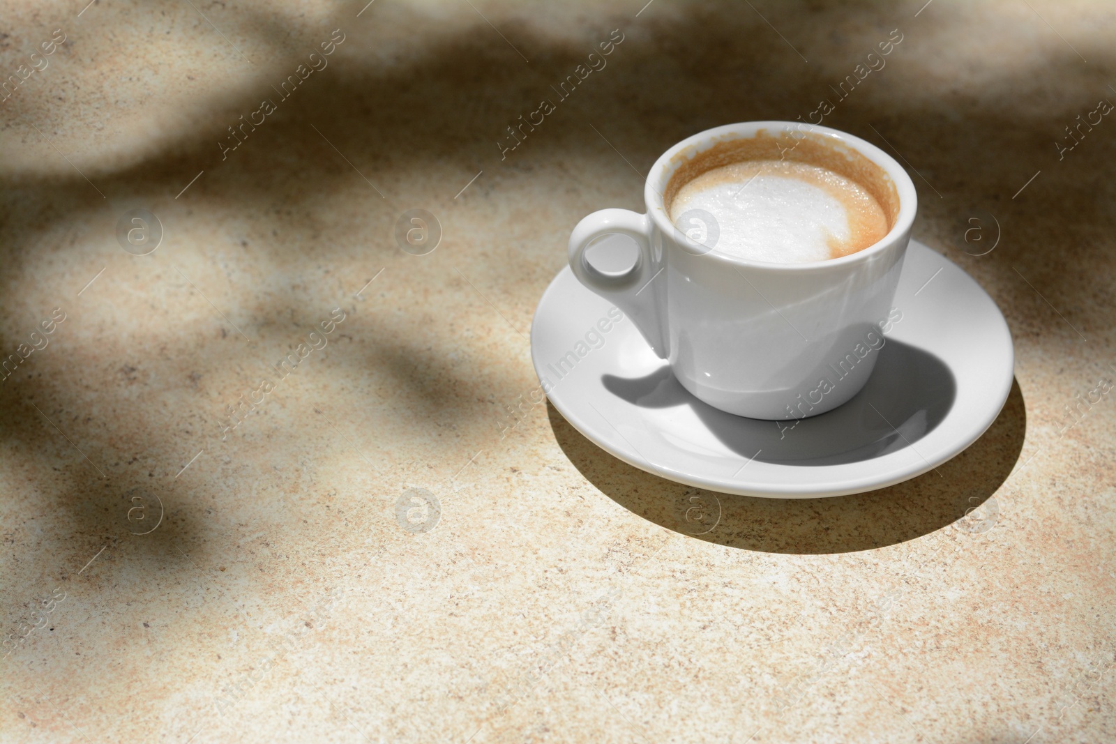 Photo of Cup of hot aromatic coffee on beige table. Space for text