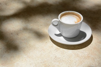 Cup of hot aromatic coffee on beige table. Space for text