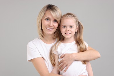 Family portrait of happy mother and daughter on grey background