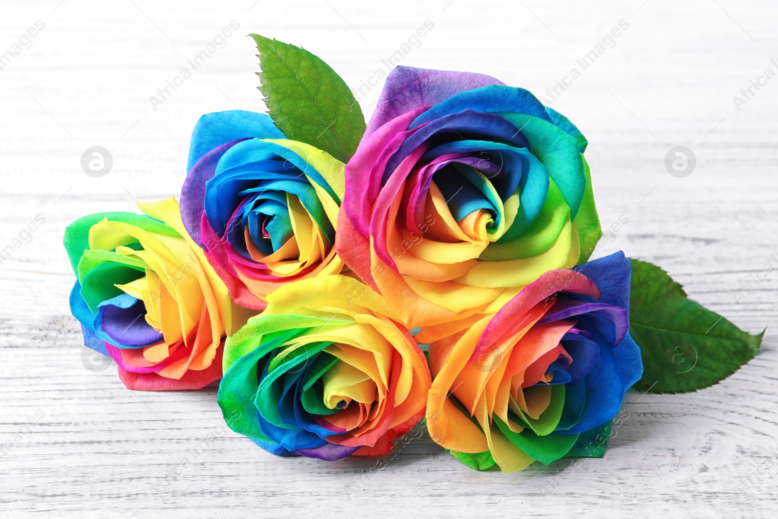 Photo of Amazing rainbow rose flowers on table