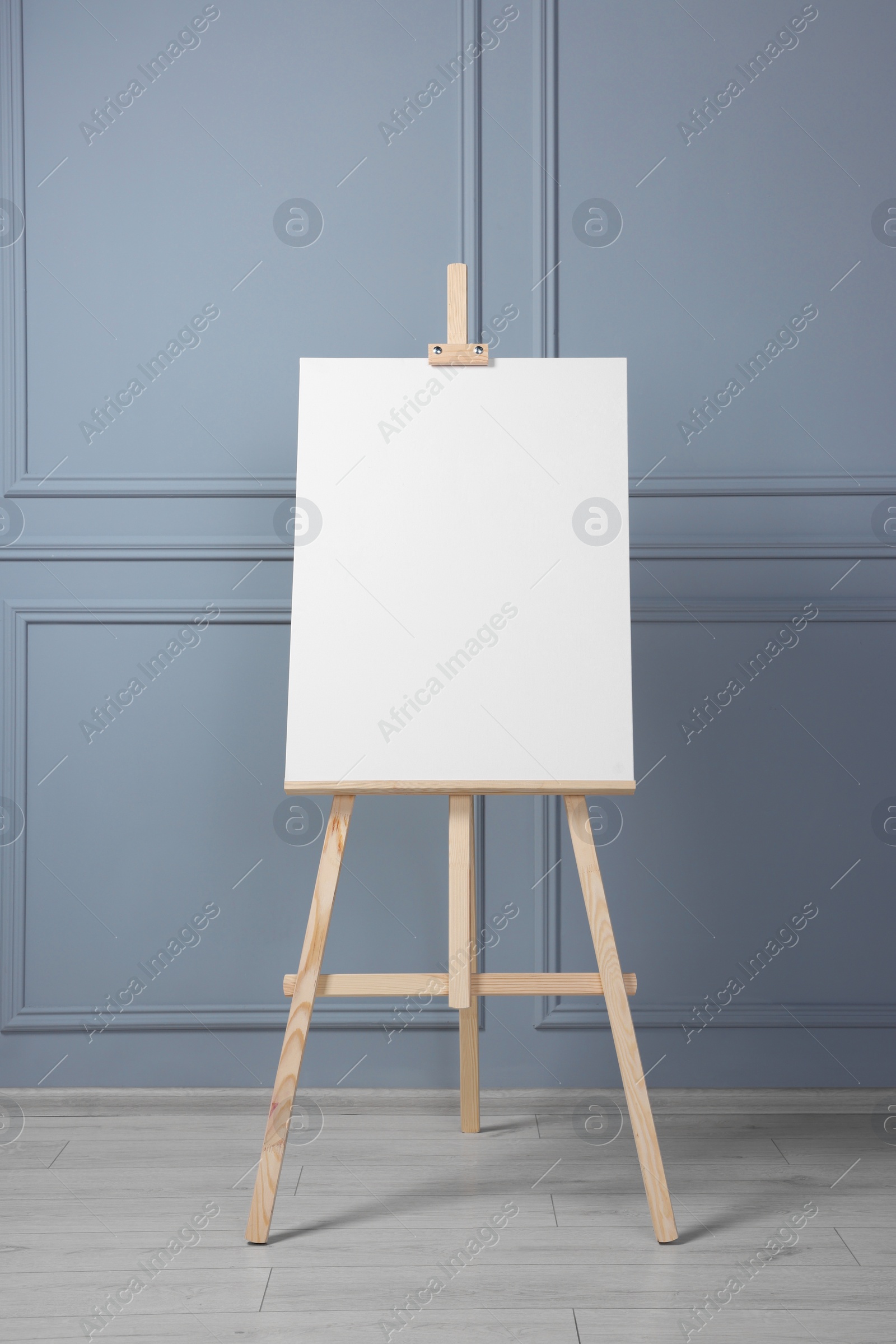 Photo of Wooden easel with blank canvas near grey wall indoors. Space for text