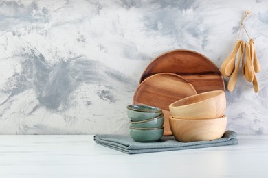 Different dishware and utensils on white marble table against textured wall. Space for text