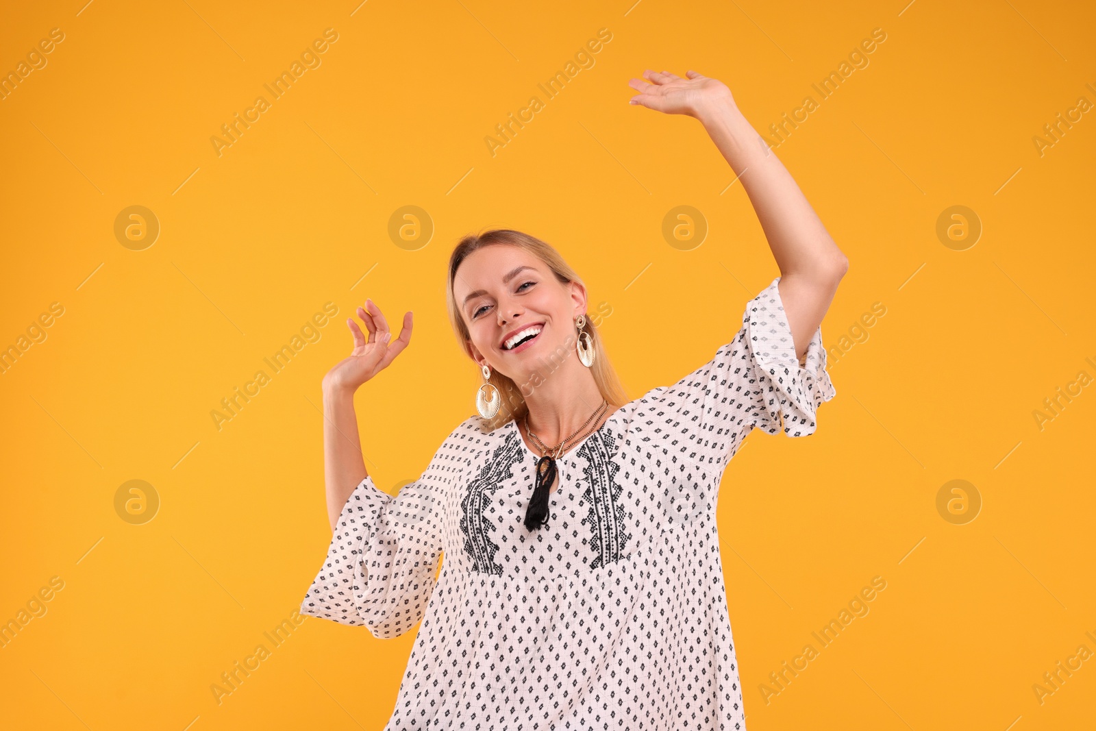 Photo of Portrait of smiling hippie woman dancing on yellow background