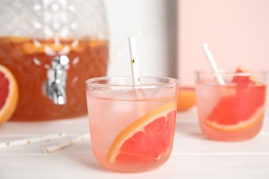 Photo of Delicious refreshing lemonade with grapefruit slices on white wooden table