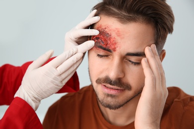 Nurse examining young man's head injury in clinic. First aid