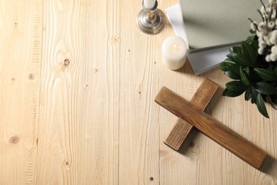Photo of Cross, candles, books and bouquet with willow branches on wooden table, flat lay. Space for text