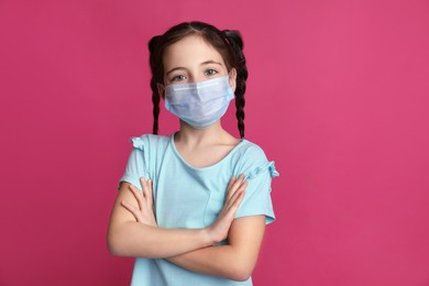 Photo of Girl wearing protective mask on pink background. Child's safety from virus