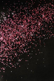 Photo of Rose gold glitter on black background, top view with space for text