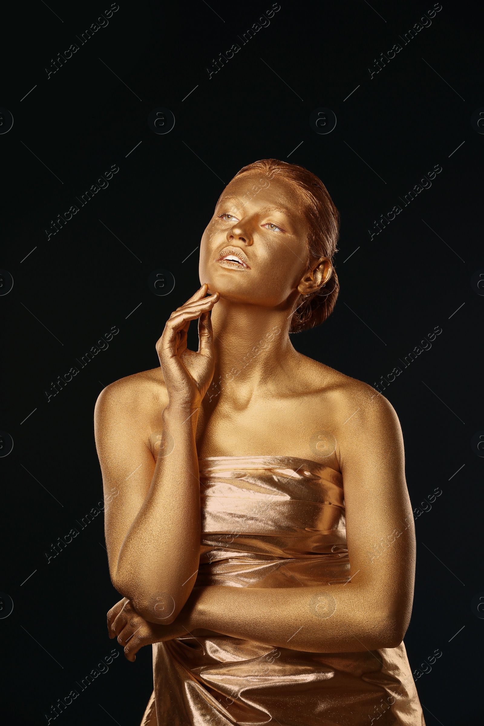 Photo of Portrait of beautiful lady with gold paint on skin against black background