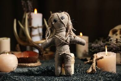 Photo of Voodoo doll pierced with pins and candles on table. Curse ceremony