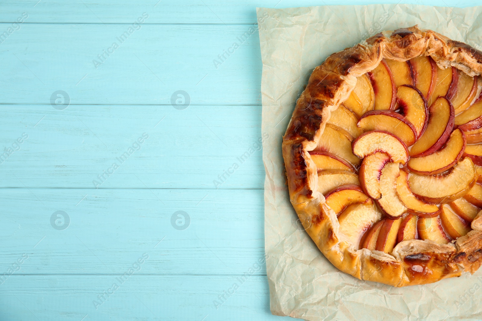 Photo of Delicious fresh peach pie on light blue wooden table, top view. Space for text