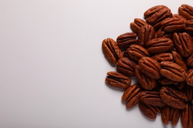 Photo of Pile of delicious fresh pecan nuts on white background, top view. Space for text