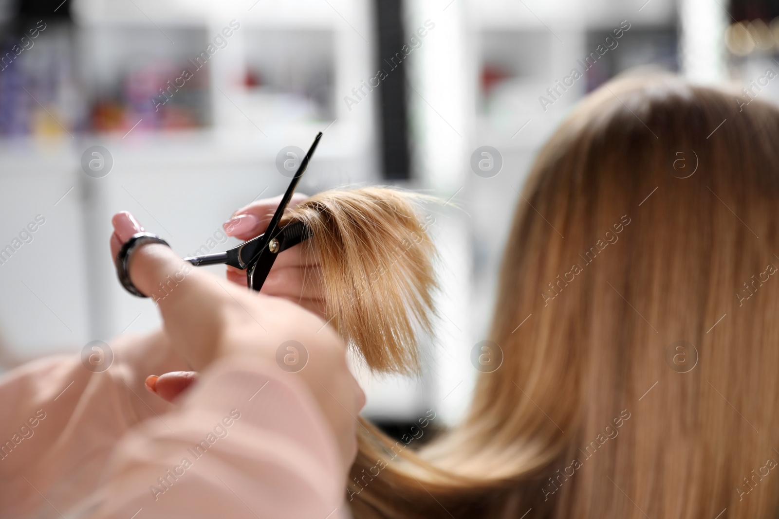 Photo of Hairdresser making stylish haircut with professional scissors in salon, closeup