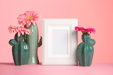 Photo of Decorative cacti, flowers and photo frame on table against color background, space for text. International Women's Day