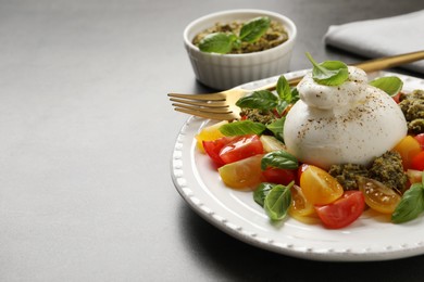 Photo of Delicious burrata salad served on grey table. Space for text