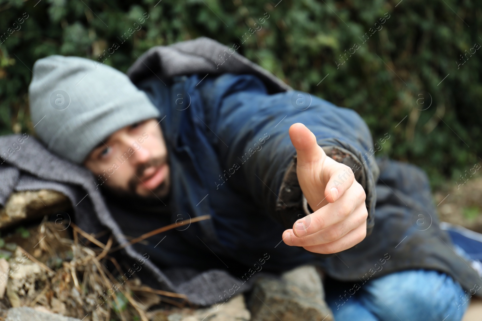 Photo of Poor homeless man with blanket on street in city