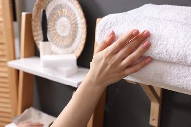 Woman stacking towels in laundry room, closeup