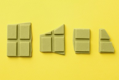 Photo of Pieces of tasty matcha chocolate bars on yellow background, flat lay