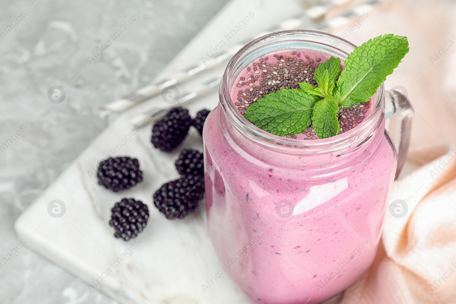 Photo of Delicious blackberry smoothie in mason jar on marble table