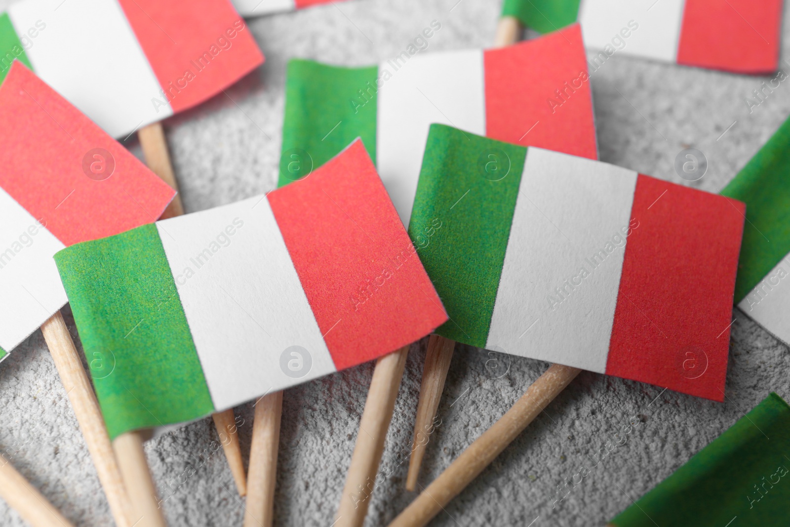 Photo of Small paper flags of Italy on grey textured table, closeup