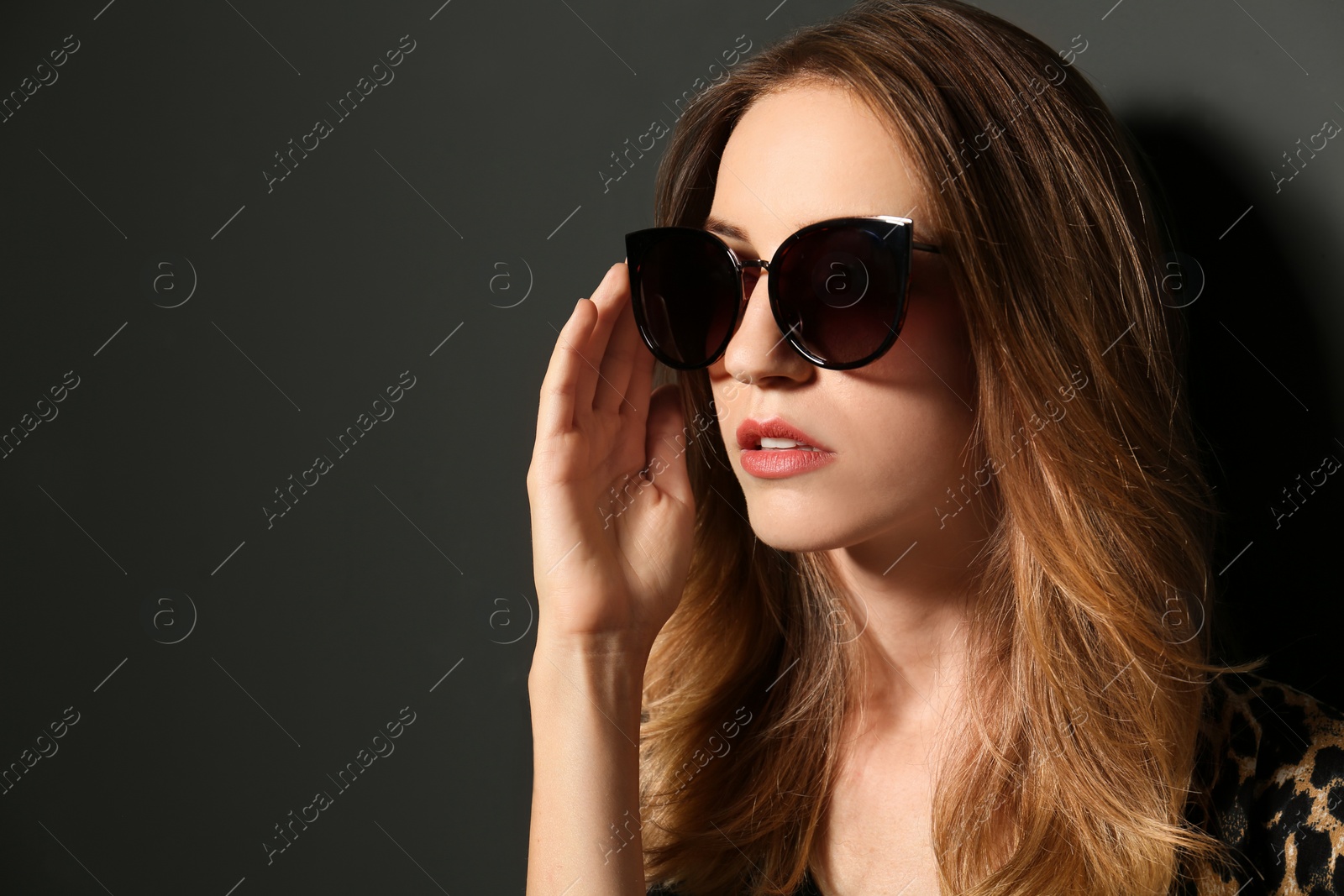 Photo of Young woman wearing stylish sunglasses on dark grey background